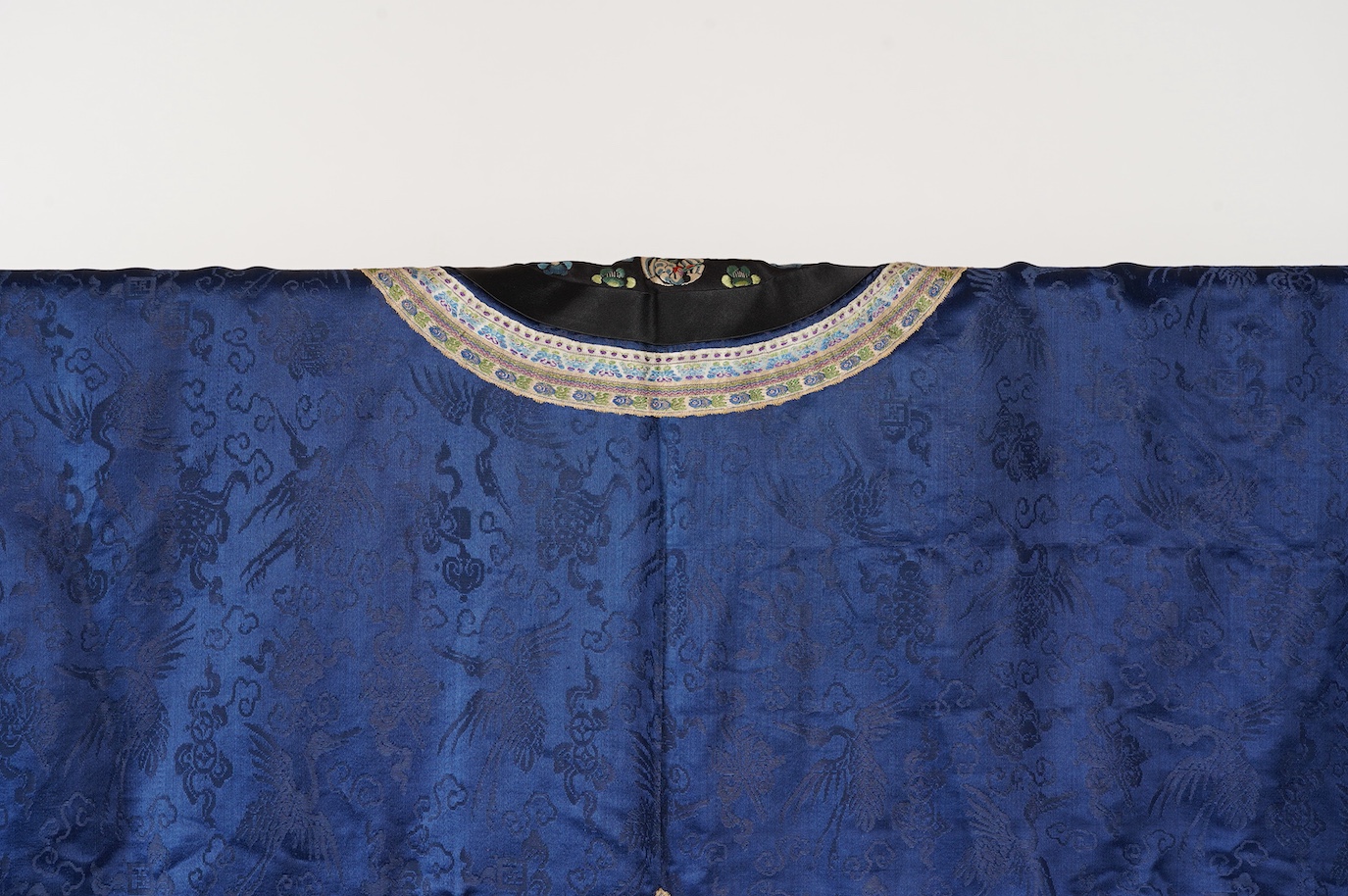 A late 19th century Chinese blue silk damask jacket, woven with Phoenix and auspicious symbols. The jacket edged with ornate rows of braiding and silk embroidery, the interior with original pink silk lining. The jacket f
